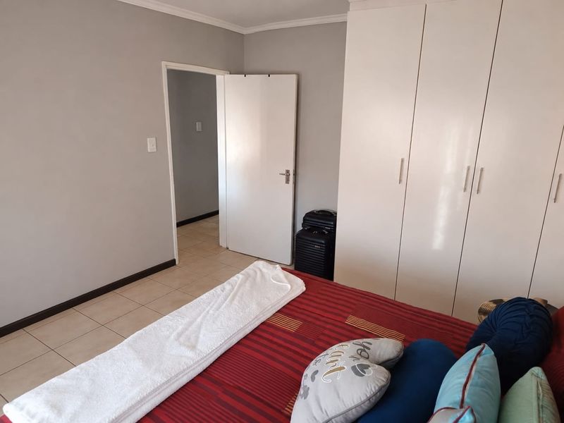 A bedroom featuring neutral wall tones, tiled flooring, and ample built-in cupboard storage space.