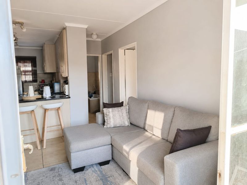 An open-plan living area featuring a modern kitchen with built-in cabinetry, granite countertops, and a breakfast bar, seamlessly connected to the lounge space.