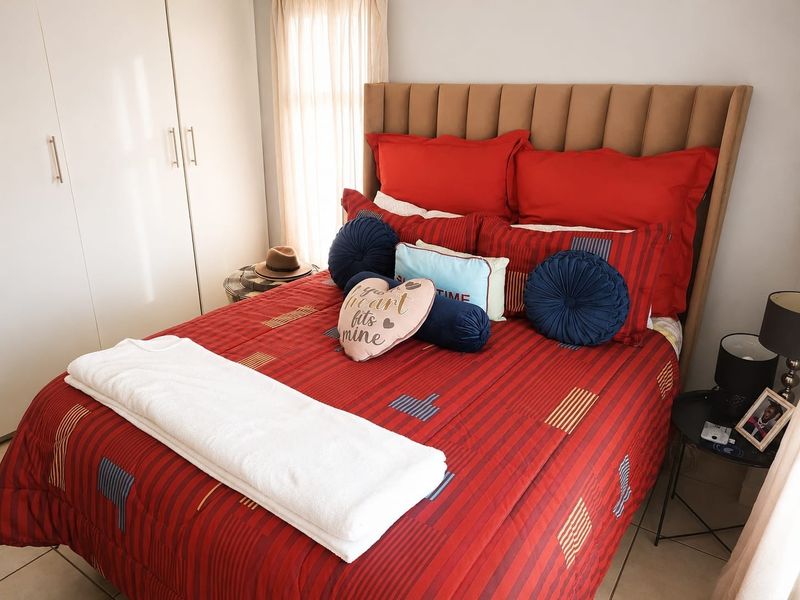 A well-maintained bedroom featuring built-in cupboards and tiled flooring, offering a clean and functional living space.