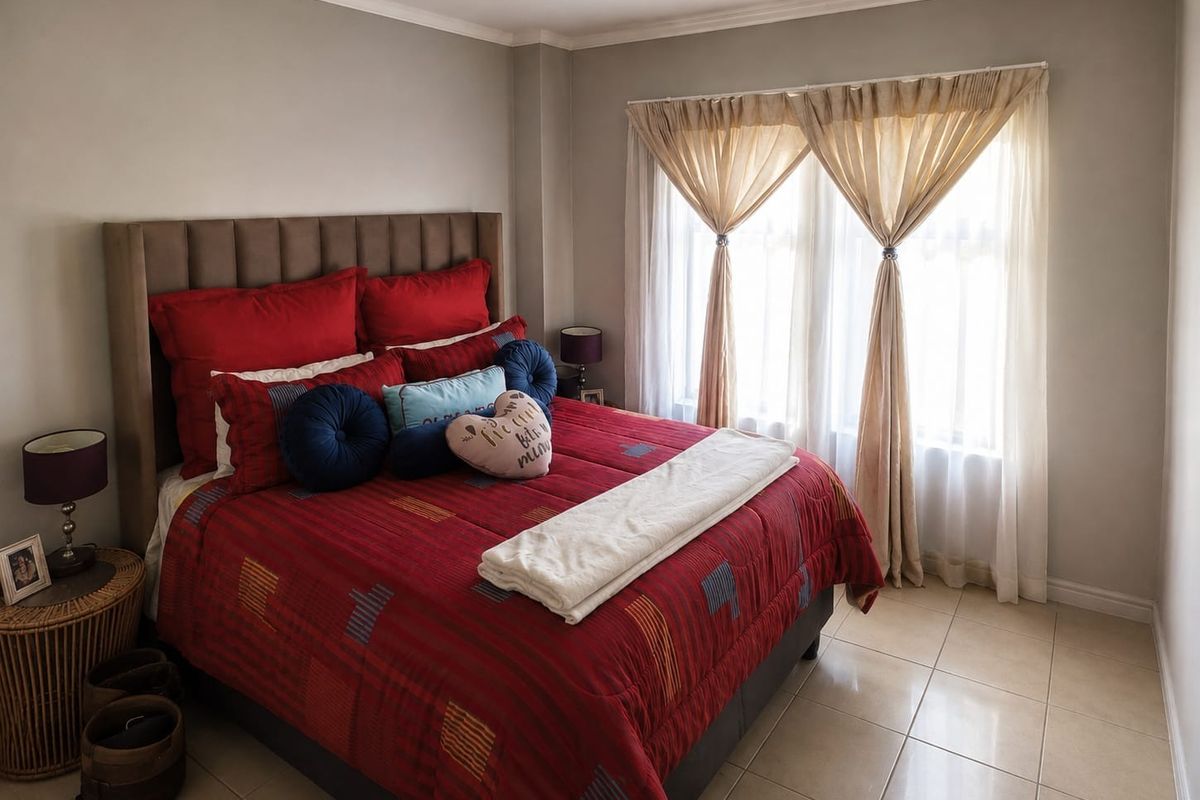A well-maintained bedroom featuring neutral wall tones, tiled flooring, and a large window allowing for natural light.