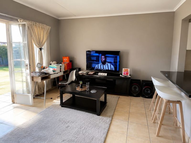 Open-plan living area featuring tiled flooring, a breakfast bar with granite countertop, and direct access to the garden through a glass sliding door.