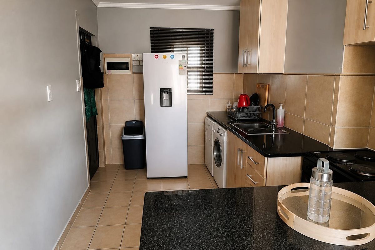 A functional kitchen featuring granite countertops, light wood cabinetry, tiled backsplash, and integrated plumbing for appliances, offering a clean and practical workspace.