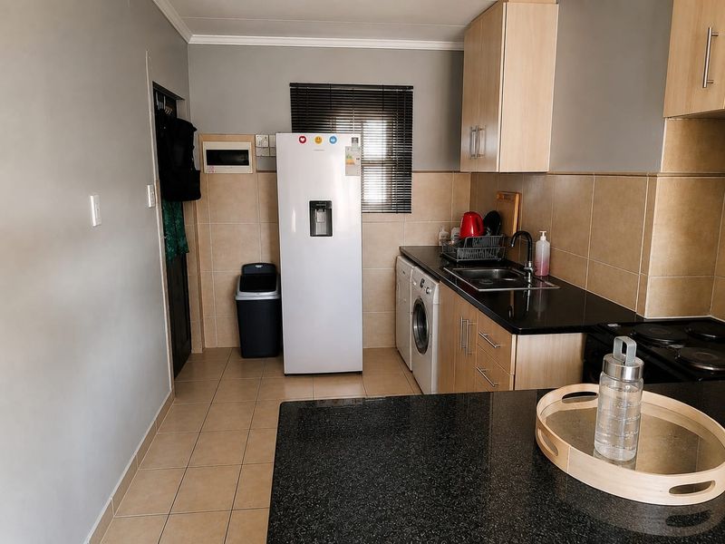 A functional kitchen featuring granite countertops, light wood cabinetry, tiled backsplash, and integrated plumbing for appliances, offering a clean and practical workspace.