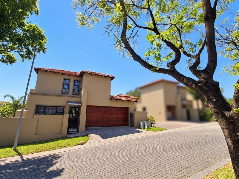 Front elevation of a modern townhouse featuring a tiled roof, paved driveway, and a secure double garage entrance.