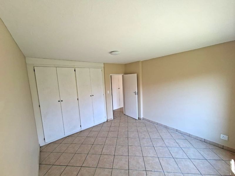 An empty bedroom featuring tiled flooring and built-in cupboards, offering a neutral canvas for personalization.