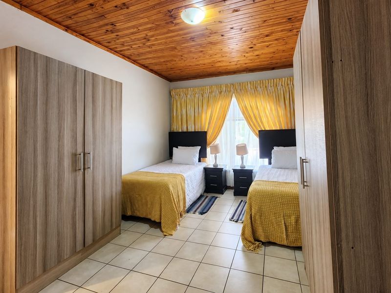A bedroom featuring tiled flooring, built-in cupboards, and a timber tongue and groove ceiling.