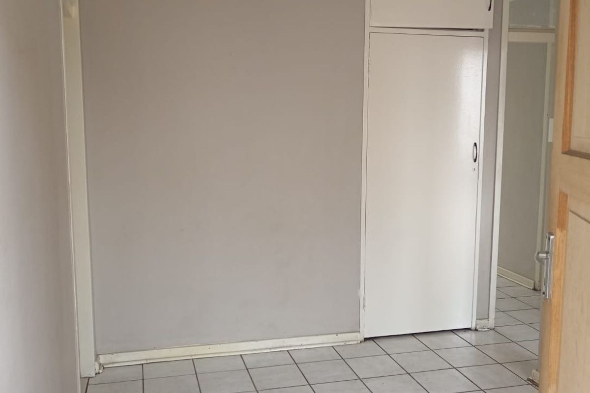 An empty bedroom featuring tiled flooring and a built-in cupboard with overhead storage.