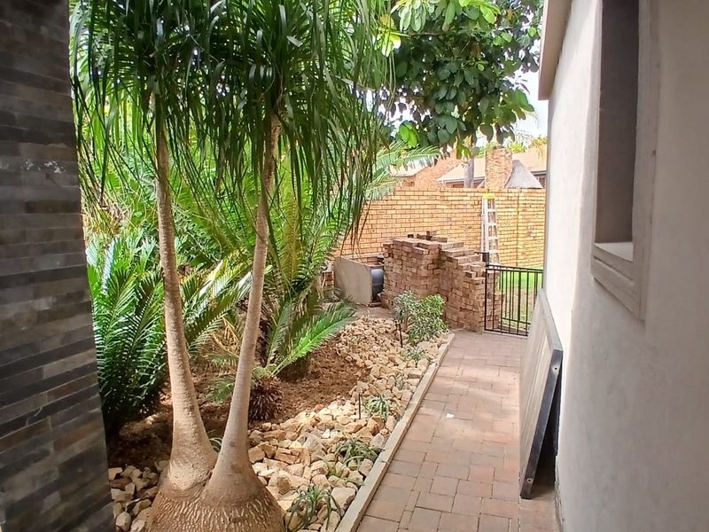 A side garden pathway featuring stone cladding, paved flooring, and a brick boundary wall, providing access to the rear of the property.