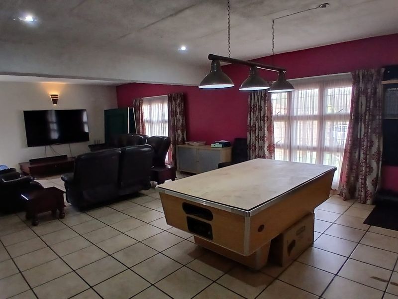 Spacious living area featuring tiled flooring, recessed lighting, and large windows, currently utilized as a multi-purpose entertainment space.
