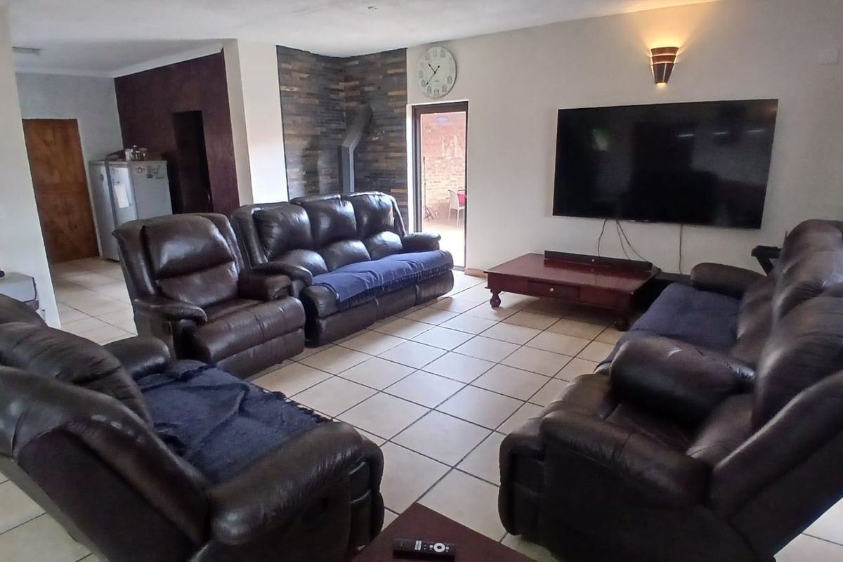 Spacious living room featuring tiled flooring, a stone accent wall, and direct access to an outdoor area through a sliding glass door.