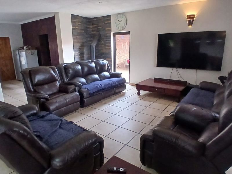 Spacious living room featuring tiled flooring, a stone accent wall, and direct access to an outdoor area through a sliding glass door.