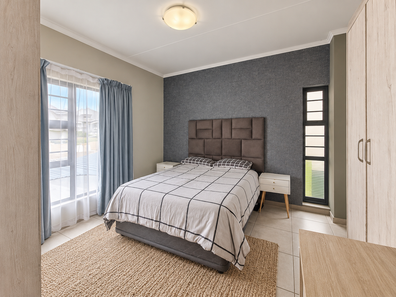 A well-maintained bedroom featuring built-in cupboards, tiled flooring, and large windows that provide ample natural light.