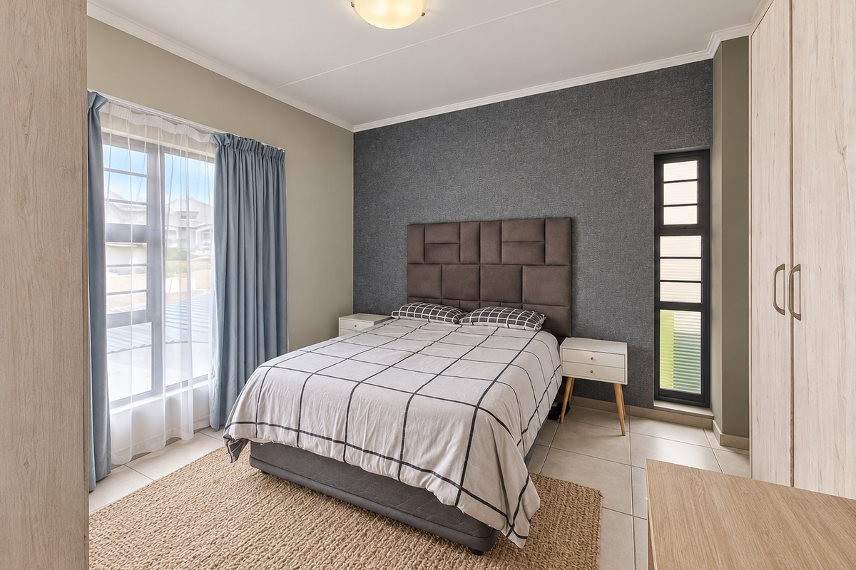 A well-maintained bedroom featuring built-in cupboards, tiled flooring, and large windows that provide ample natural light.