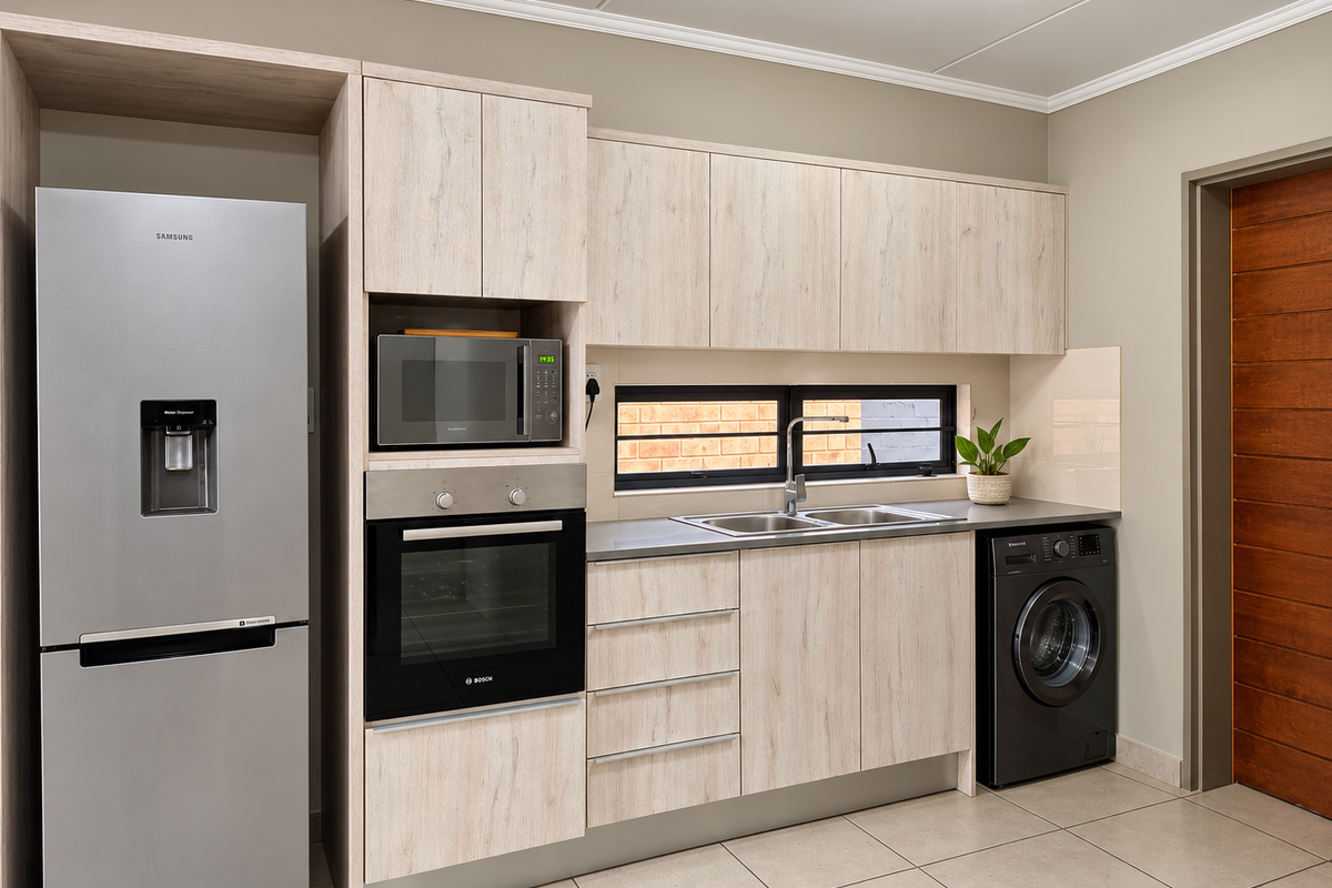 Modern kitchen featuring light wood-grain cabinetry, built-in Bosch oven and microwave, stainless steel sink, and tiled flooring with a clean, contemporary finish.
