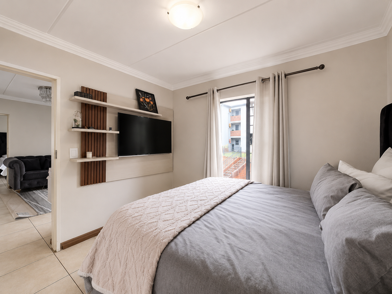 A well-maintained bedroom featuring tiled flooring, a built-in shelving unit, and a sliding glass door providing access to the exterior.
