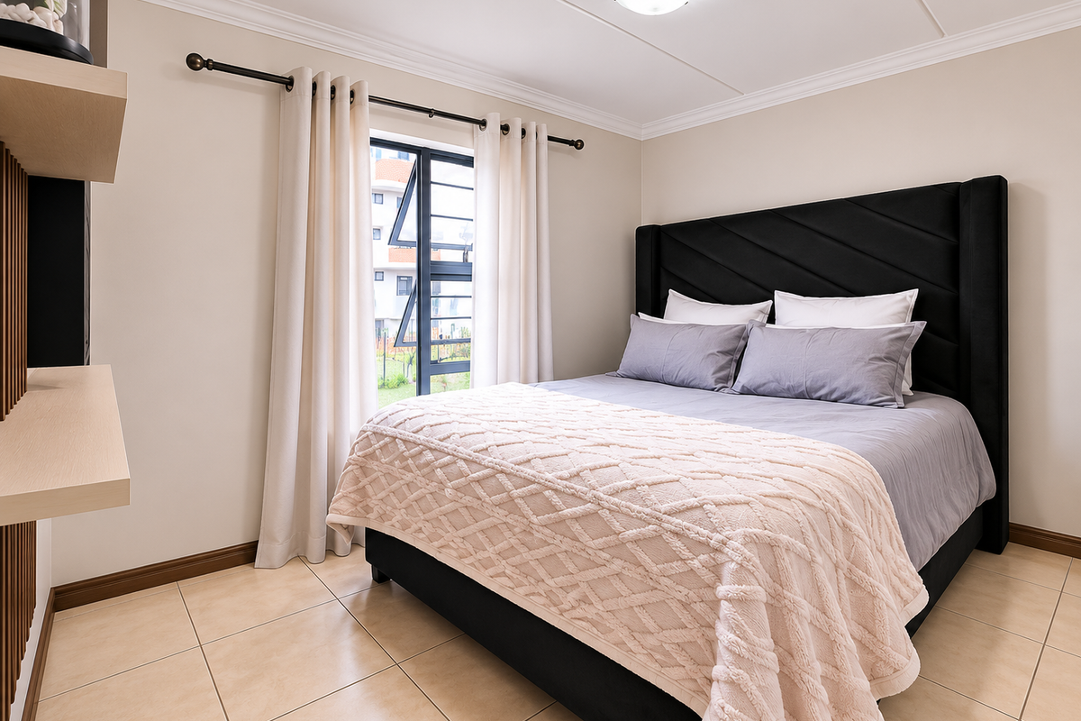 A well-maintained bedroom featuring neutral tiled flooring, built-in shelving, and a window with curtain rod, providing a clean and comfortable living space.