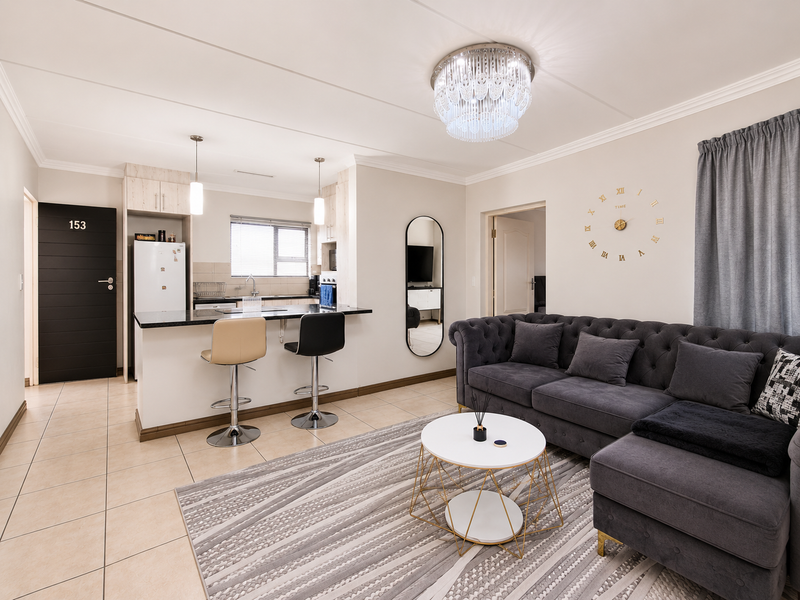 A well-maintained open-plan living and kitchen area featuring tiled floors, modern cabinetry, granite countertops, and stylish lighting fixtures.