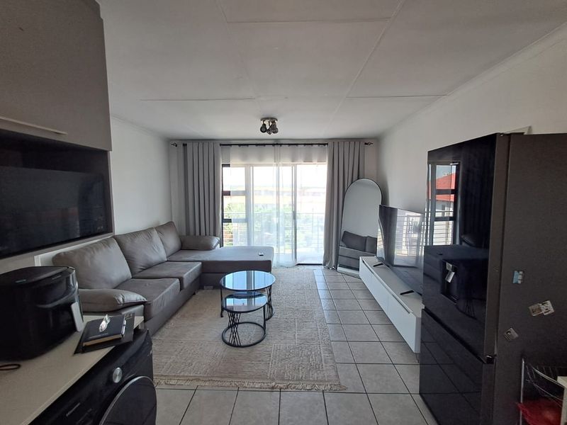 A functional living room featuring tiled flooring and a sliding glass door that provides access to an outdoor balcony area.