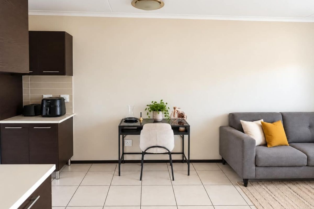 An open-plan living area featuring dark wood kitchen cabinetry, neutral tiled flooring, and a clean, functional layout suitable for modern living.
