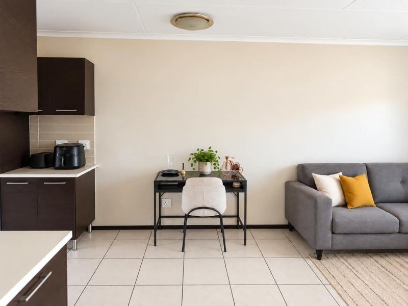 An open-plan living area featuring dark wood kitchen cabinetry, neutral tiled flooring, and a clean, functional layout suitable for modern living.