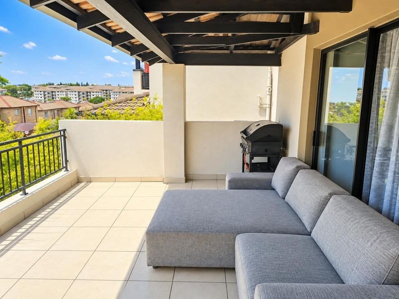 A covered balcony featuring tiled flooring, exposed timber beams, and a metal balustrade, offering an open outdoor space with elevated views.