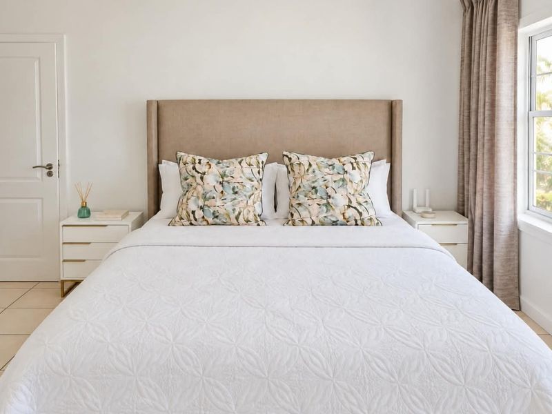 A well-maintained bedroom featuring neutral tiled flooring, a classic panel door, and a sash window with natural light.