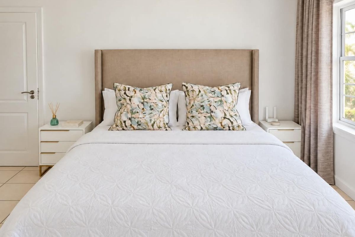 A well-maintained bedroom featuring neutral tiled flooring, a classic panel door, and a sash window with natural light.