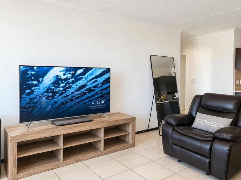 A bright and well-maintained living area featuring neutral tiled flooring and coved ceilings, providing a clean and functional space.