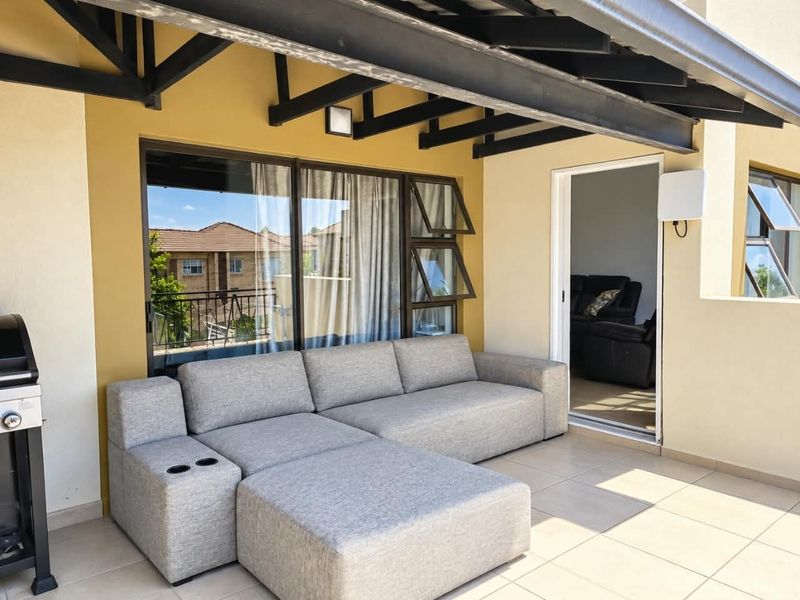 A covered patio area featuring tiled flooring, a sturdy roof structure, and direct access to the interior living space through sliding glass doors.