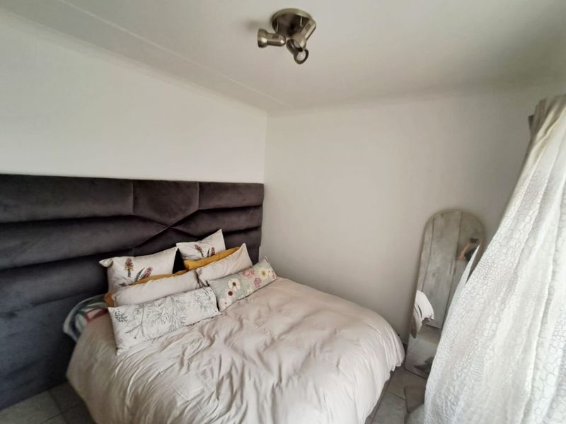 A well-maintained bedroom featuring tiled flooring and a modern ceiling-mounted spotlight fixture.