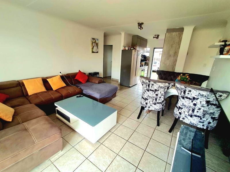 Open-plan living and dining area featuring tiled flooring and a connected kitchen space with built-in cabinetry.