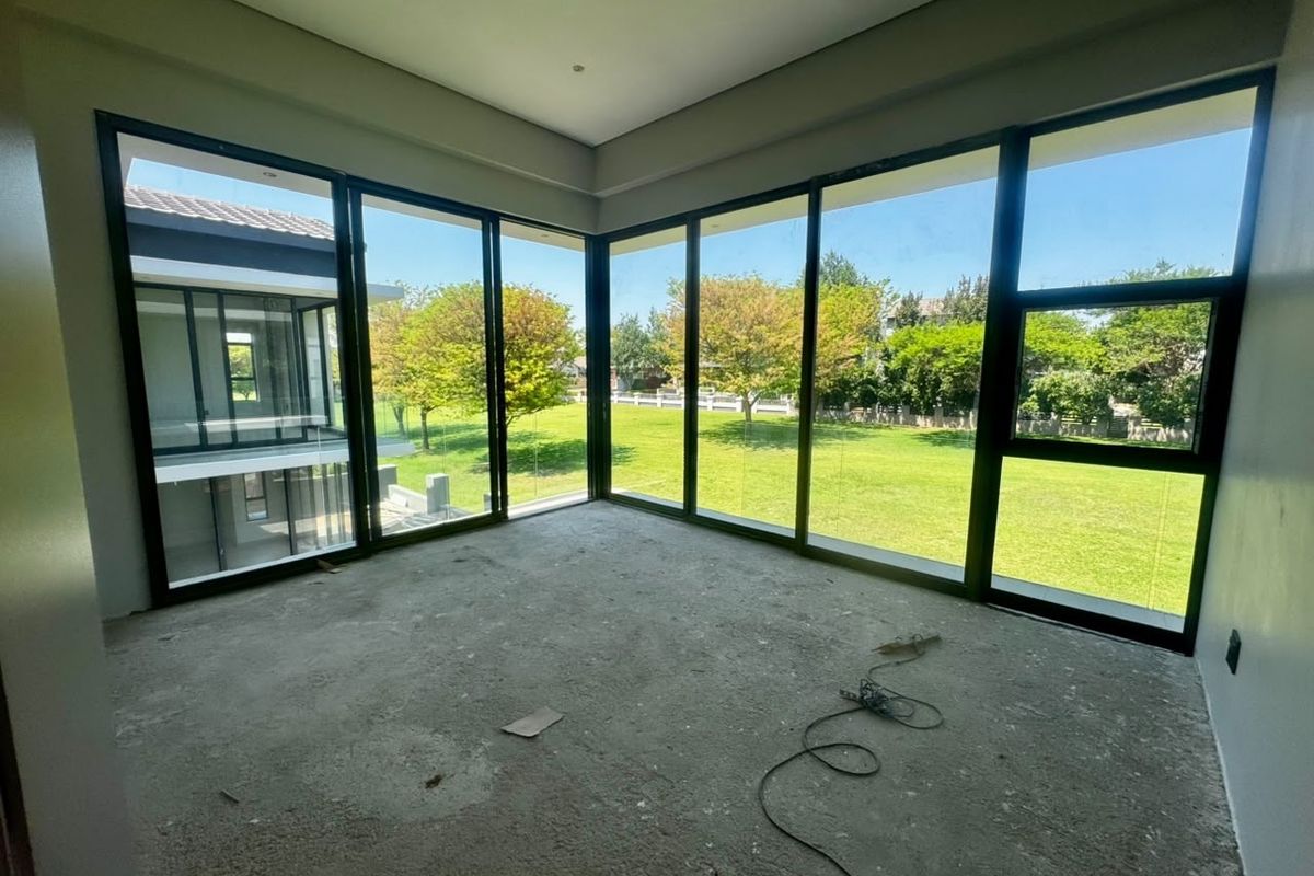 An unfinished bedroom space featuring expansive corner windows with views of the garden and surrounding estate.