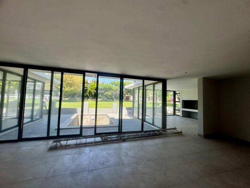 Spacious open-plan living area featuring large sliding glass doors that open onto a patio and pool area, with a built-in fireplace.
