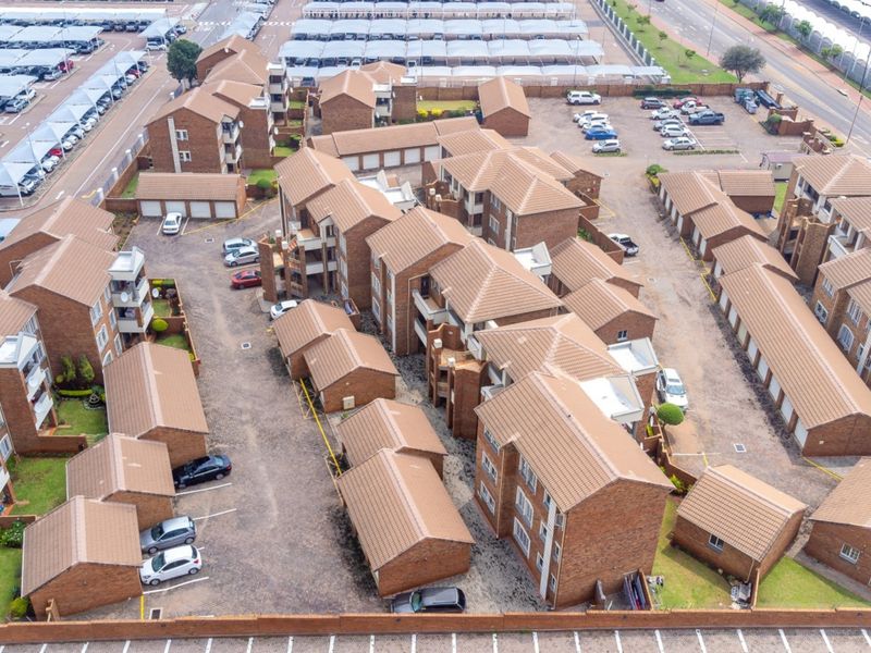Aerial view of a residential flat complex featuring multiple brick buildings with tiled roofs, paved driveways, and dedicated parking areas.