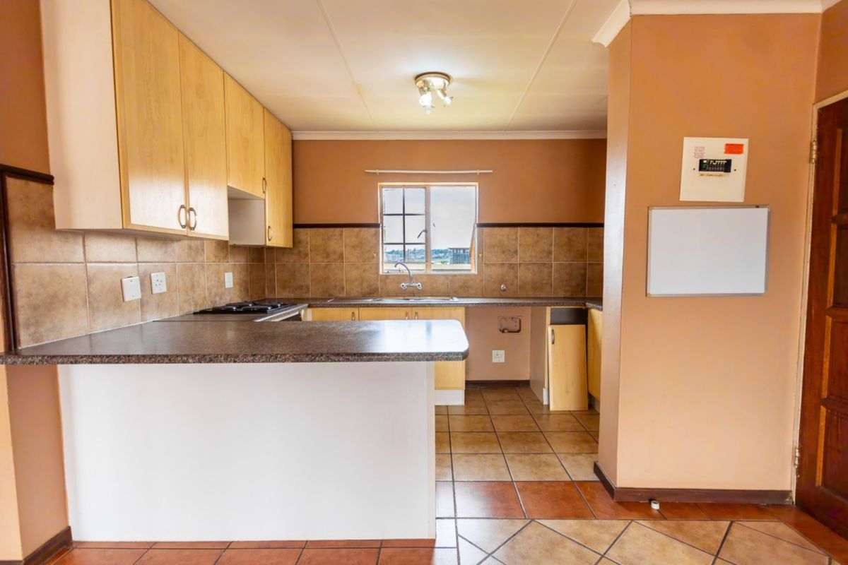 A functional kitchen featuring laminate cabinetry, tiled backsplash, and a built-in hob, offering a practical layout with potential for modern updates.