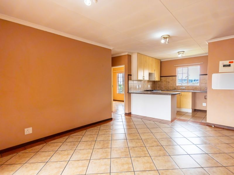An open-plan living and kitchen area featuring tiled flooring, built-in cabinetry, a kitchen peninsula, and a tiled backsplash.