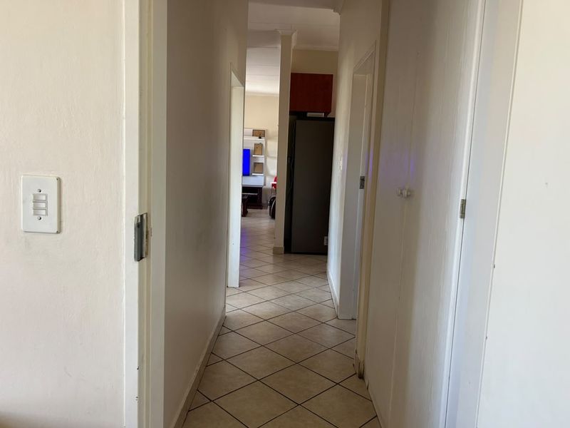 A functional hallway with tiled flooring connecting various rooms, providing a clear view through to the living area.
