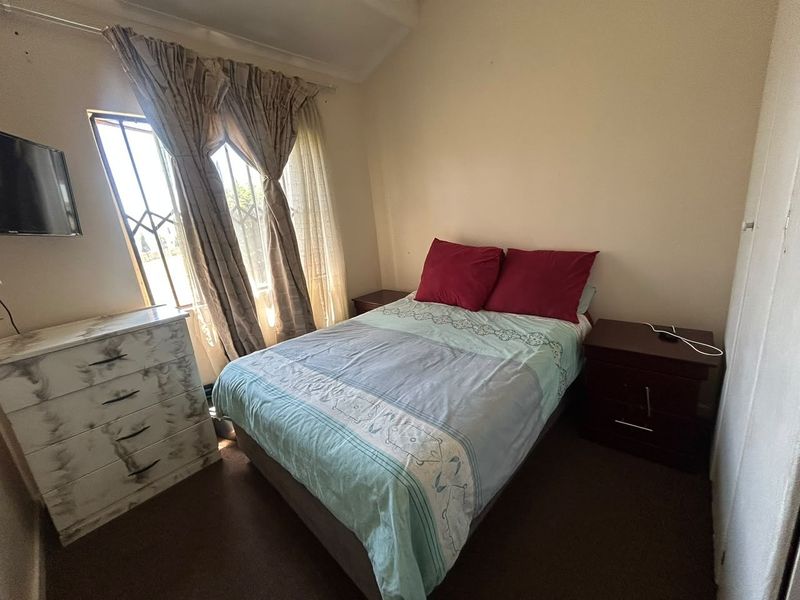A standard bedroom featuring security bars on the window and a built-in cupboard, offering a functional space with neutral wall finishes.