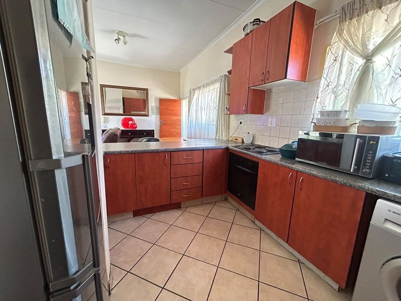 Functional kitchen featuring wood-tone cabinetry, laminate countertops, built-in oven and hob, and tiled flooring, offering a practical layout for daily meal preparation.