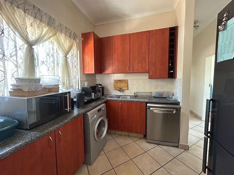 Functional kitchen featuring warm-toned laminate cabinetry, granite countertops, tiled backsplash, and dedicated spaces for a dishwasher and washing machine.