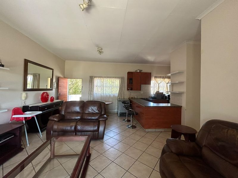 Open-plan living and kitchen area featuring tiled flooring, a breakfast bar, and functional cabinetry, offering a versatile space for daily living.