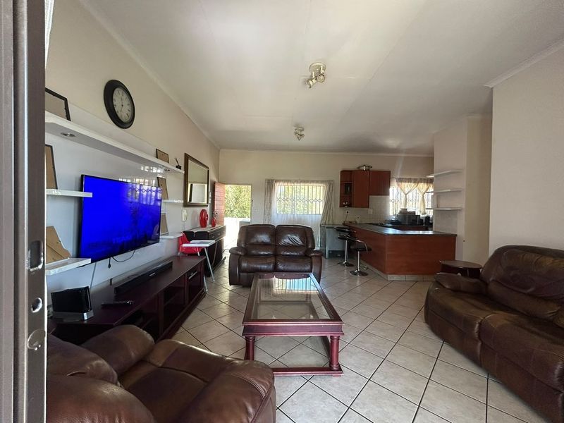 Open-plan living and kitchen area featuring tiled flooring, built-in cabinetry, and a breakfast bar, offering a functional layout for daily living.