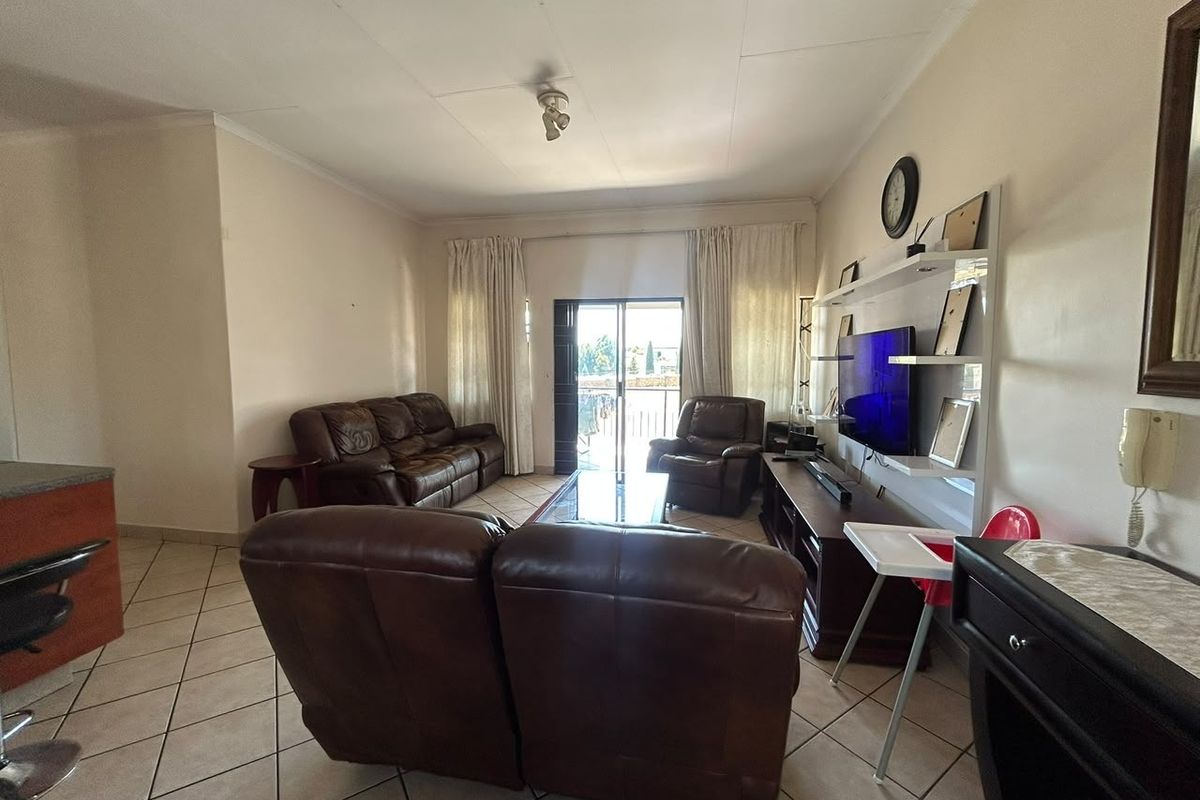 A spacious living room featuring tiled flooring, a built-in shelving unit, and sliding glass doors that provide access to an outdoor area.