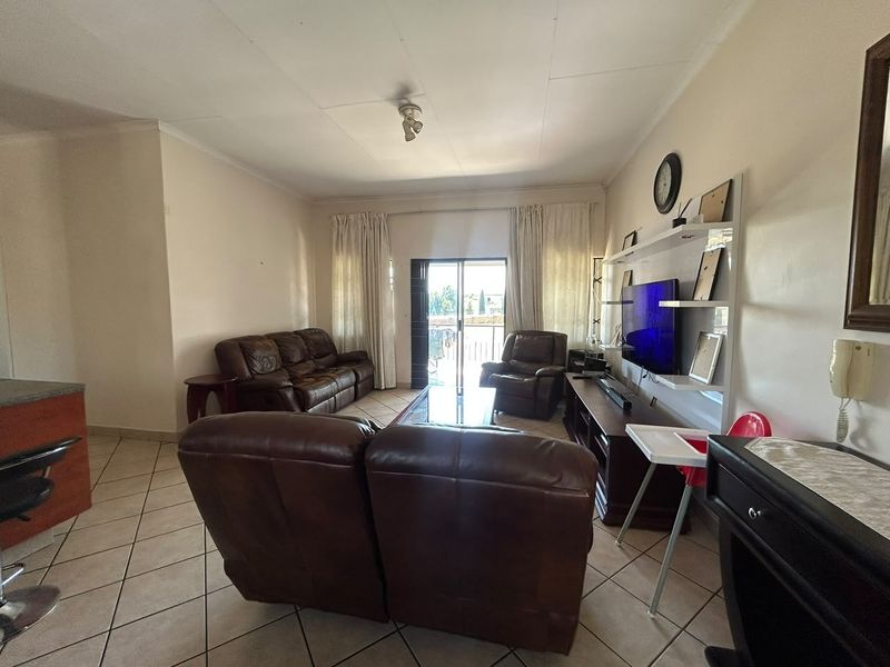 A spacious living room featuring tiled flooring, a built-in shelving unit, and sliding glass doors that provide access to an outdoor area.