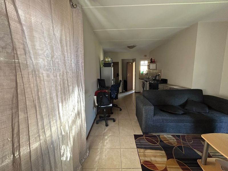 Open plan living area featuring tiled flooring and a compact kitchen space with built-in cabinetry and appliances.