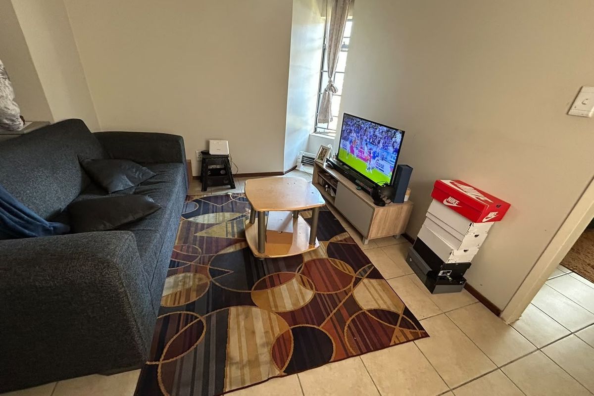 A compact living room area featuring tiled flooring and a window, providing a functional space for relaxation.