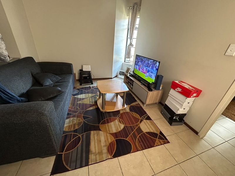 A compact living room area featuring tiled flooring and a window, providing a functional space for relaxation.