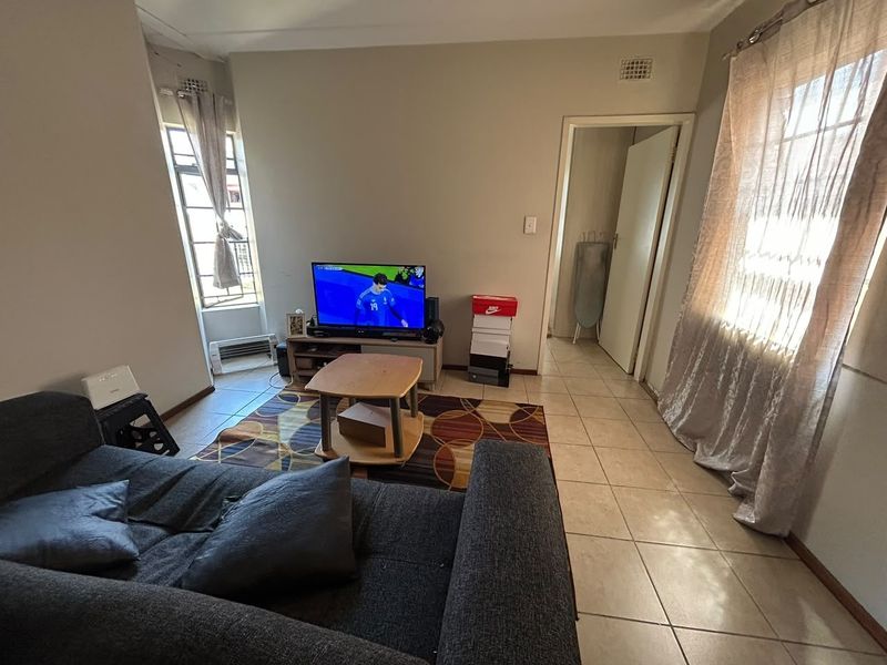 A living room area featuring tiled flooring and natural light from windows, providing a functional space for relaxation.