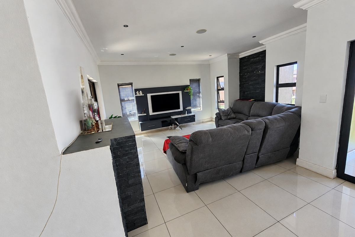 Spacious living room featuring polished tile flooring, a modern stone feature wall, built-in media cabinetry, and recessed lighting throughout.