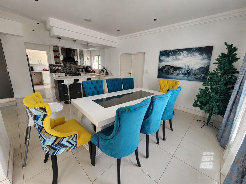 Spacious open-plan dining and kitchen area featuring a modern kitchen island, built-in appliances, and neutral tiled flooring throughout.
